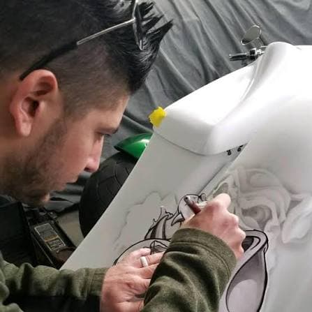 Carl Avery airbrushing a design onto a white surface in his studio